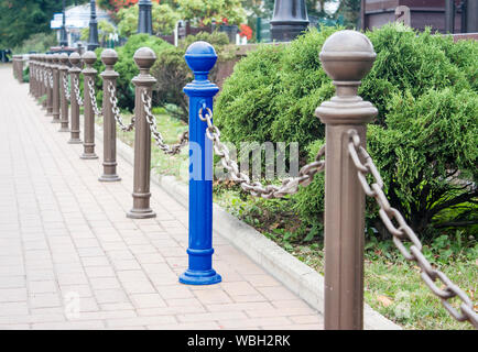 decorative fence made of metal posts in a city park on summer day. concept i am different from others Stock Photo