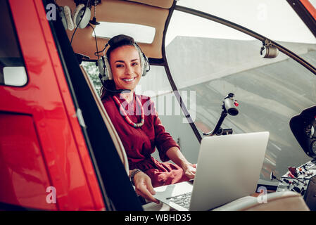 Businesswoman using laptop sitting in helicopter before flying Stock Photo