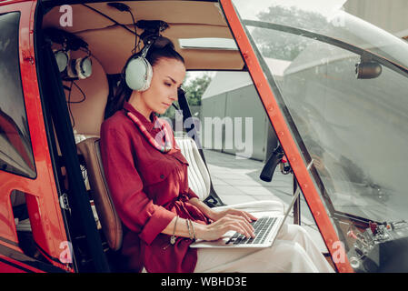 Busy woman finishing the report on laptop sitting in helicopter Stock Photo