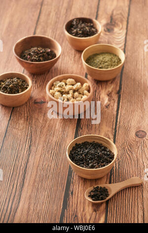 assortment of dry tea in white bowls on wooden surface Stock Photo