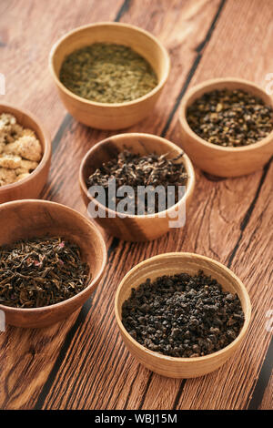 assortment of dry tea in white bowls on wooden surface Stock Photo