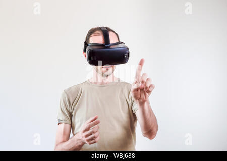 Caucasian man in t-shirt wearing virtual reality goggles on white background. Future technology concept. Stock Photo