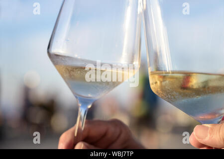 toast with cold white wine on a sunny summer evening during the holidays, concept for enjoyment and lifestyle, close-up Stock Photo