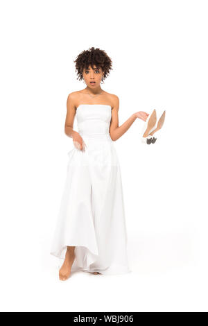 African American Bride Touching Wedding Dress And Holding Shoes