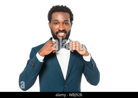 happy african american bridegroom smiling white touching bow tie isolated on white Stock Photo