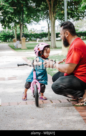 Young father spend time with Cute little Asian 2 years old toddler girl child, Dad and child having fun with balance bike (run bike) on nature, Dad te Stock Photo