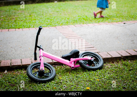 Pink bike for the little girl. A pink bike parking in the park near the pavement. Stock Photo