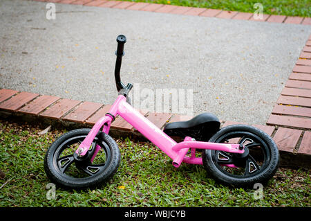 Pink bike for the little girl. A pink bike parking in the park near the pavement. Stock Photo