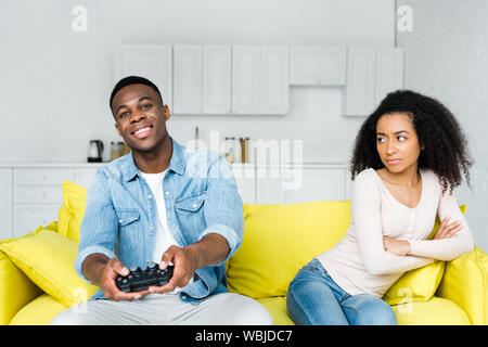 KYIV, UKRAINE - MAY 13, 2019: african american man playing in video games, sitting near offended woman Stock Photo