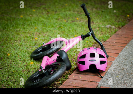 Pink bike for little girl. A pink bike parking in the park near the pavement. Stock Photo