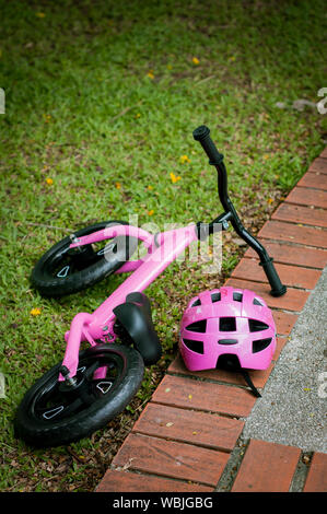 Pink bike for little girl. A pink bike parking in the park near the pavement. Stock Photo