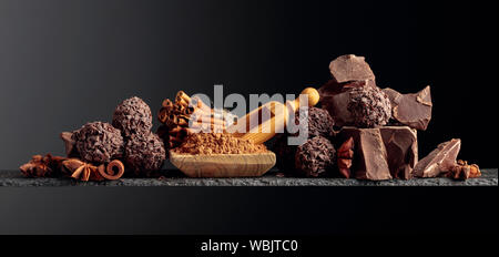 Chocolate truffles with broken pieces of chocolate and spices. Chocolate, cinnamon sticks and anise on a dark background. Copy space. Stock Photo