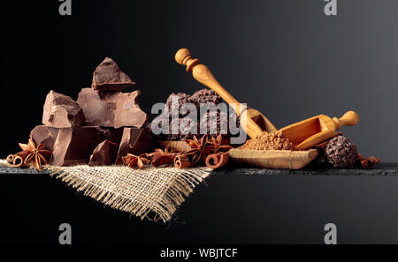 Chocolate truffles with broken pieces of chocolate and spices. Chocolate, cinnamon sticks and anise on a dark background. Copy space. Stock Photo