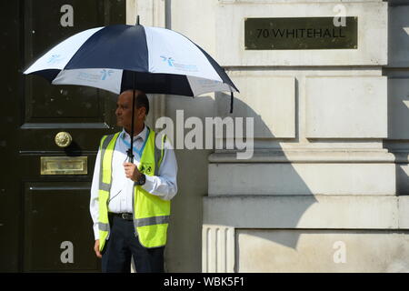 A security guard shades himself from the sun outside the Cabinet Office in London, ahead of today's cross party meeting looking at ways to stop a no deal Brexit. Stock Photo