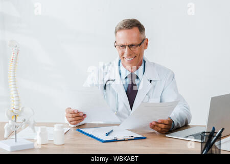 happy doctor in glasses looking at documents in clinic Stock Photo