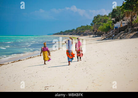 Zanzibar beach local Muslim women in national bright clothes walk on the beach Stock Photo