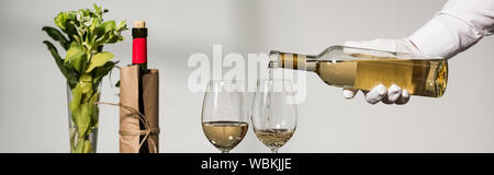 panoramic shot of waiter in white glove pouring wine in wine glasses Stock Photo