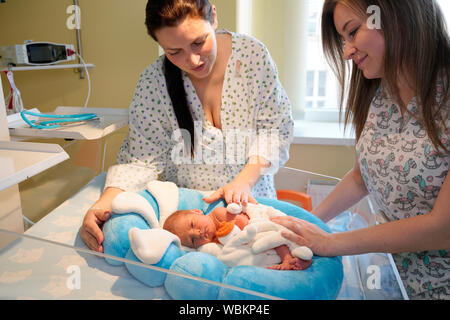 Mother with a nurse takes care of newborns in intensive care Stock Photo