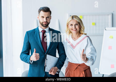 handsome recruiter and blonde woman showing thumbs up in office Stock Photo