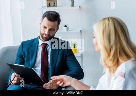 selective focus of handsome recruiter with clipboard near woman pointing with finger Stock Photo