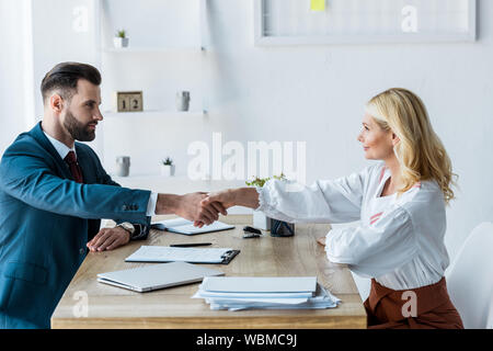 selective focus of handsome recruiter and attractive employee shaking hands Stock Photo