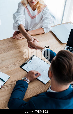overhead view of recruiter and happy employee shaking hands in office Stock Photo