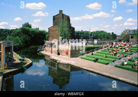 People sitting on terraces by the Regents Canal at the newly developed Coal Drops Yard, King's Cross, London UK Stock Photo
