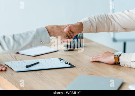 cropped view of man and woman shaking hands near table Stock Photo