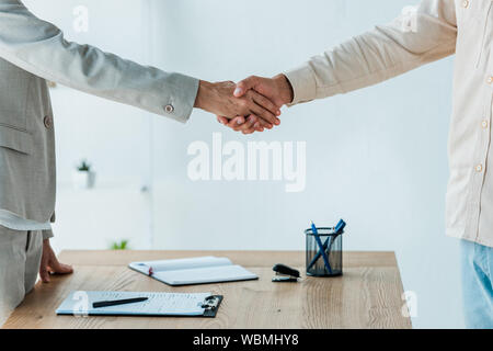 cropped view of man and recruiter shaking hands near table Stock Photo