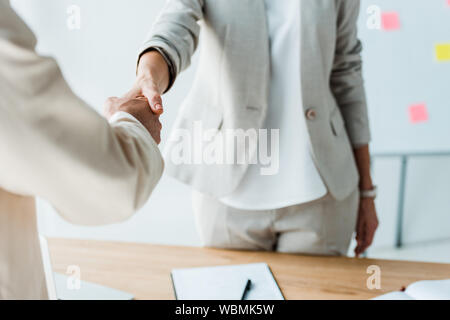cropped view of recruiter and employee shaking hands while standing  in office Stock Photo