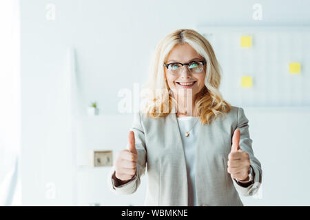 cheerful recruiter in glasses showing thumbs up in office Stock Photo
