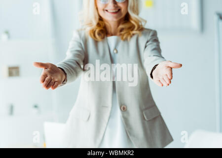 cropped view of cheerful blonde woman gesturing in office Stock Photo