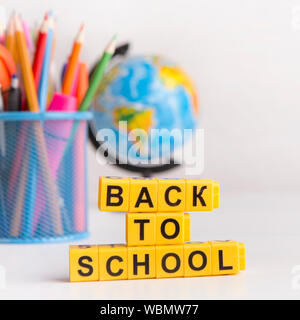 Back to school text on yellow cubes, school supplies on white Stock Photo