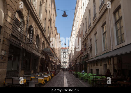 LYON, FRANCE - JULY 19, 2019: Typical narrow street of the Vieux Lyon (old Lyon) on the Presqu'ile district with tourists passing by near restaurants Stock Photo