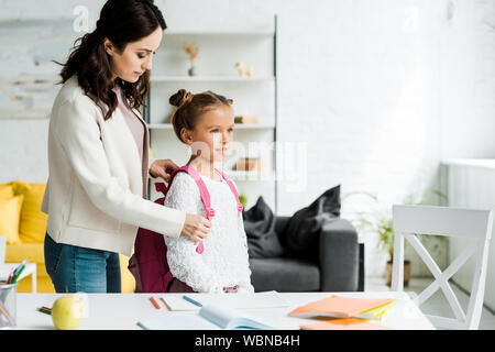 attractive mother taking off backpack of cute daughter Stock Photo