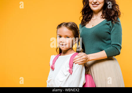 cropped view of mother touching shoulders of daughter isolated on orange Stock Photo