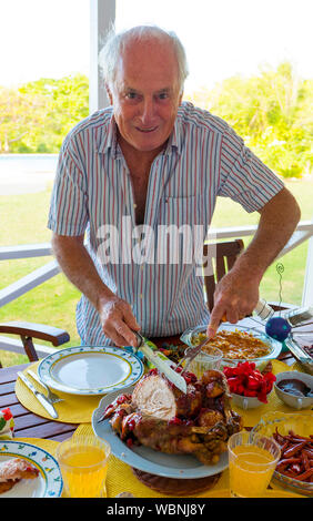 Man carving the Xmas turkey on the lunchtime table in the caribbean . Stock Photo