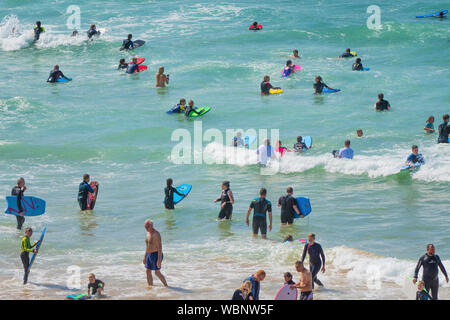 Holidaymakers on a staycation holiday enjoying themselves in the sea at Fistral in Newquay in Cornwall.