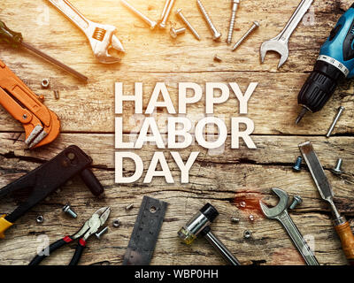 Happy Labor day text in white color on wooden background with construction repair tools. Stock Photo