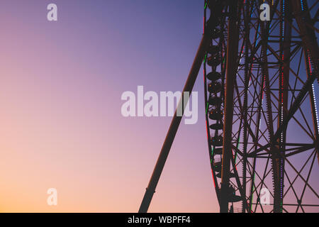 Observation wheel silhouette in bright evening sky. Fairground ride and beautiful evening sky, bright and vivid moody colors. Stock Photo