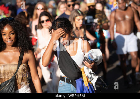 a woman holding her forehead on the hottest Notting Hill Carnival, London, UK. People in the background Stock Photo