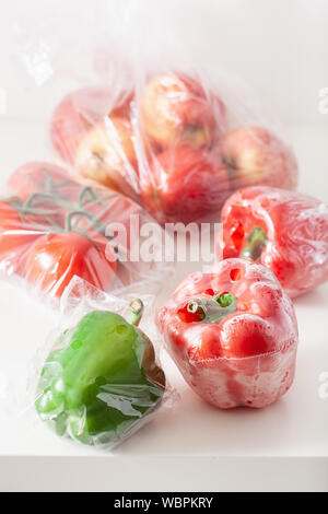 single use plastic packaging issue. peppers tomatoes apples vegetables in plastic bags Stock Photo