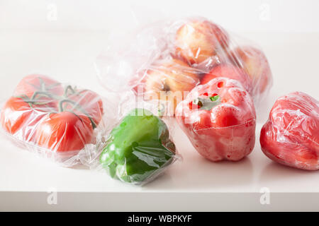 single use plastic packaging issue. peppers tomatoes apples vegetables in plastic bags Stock Photo