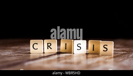 Crisis word made of tiles on dark wooden background Stock Photo