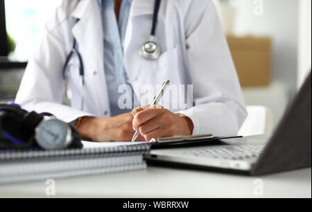 Hands of female GP making notes with silver pen Stock Photo
