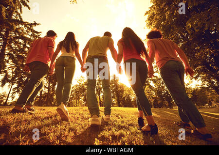 A group of happy people at sunset on the nature. Stock Photo