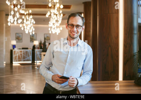 Happy young successful businessman developer keeps phone. Stock Photo