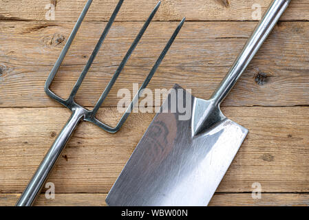 Garden fork and spade, on a wooden background. Stock Photo