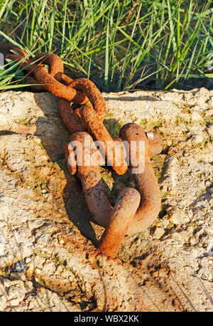 A heavy rusting chain set in a concrete block used as a boat mooring point at Wells-next-the-Sea, Norfolk, England, United Kingdom, Europe. Stock Photo