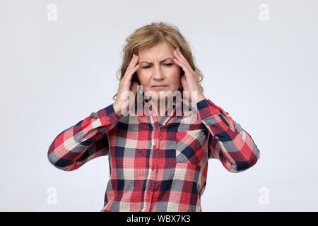Mature caucasian woman suffering from headache and pain. Studio shot Stock Photo